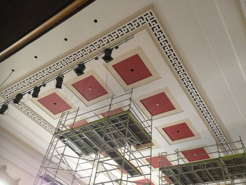 Ceiling design with red accents and intricate molding at The Victoria Rooms, Bristol.