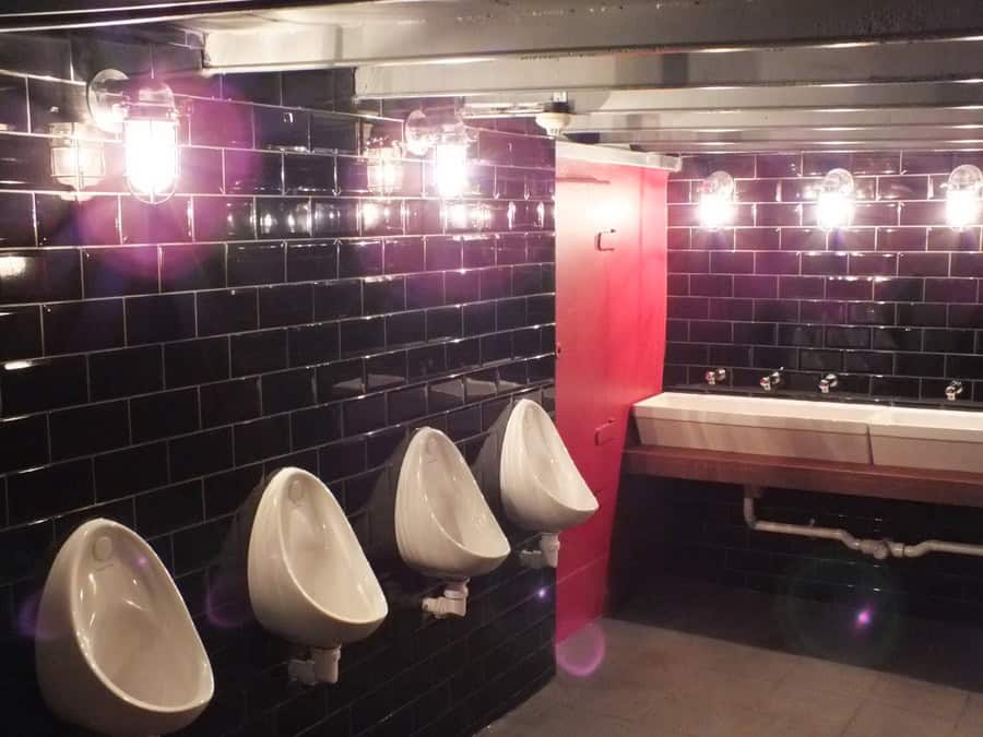 Clean, contemporary bathroom featuring black subway tiles, urinals, and a double sink setup.